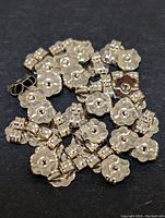 Multiple small 10K gold butterfly clutch earring backs arranged closely together on a dark surface, showing their size and shape clearly.