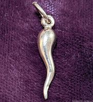 Close-up photo of the gold pendant showing curved horn shape on a purple fabric background.