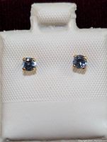 Front-facing view of the pair of 14K gold tanzanite stud earrings set on a white textured display card.