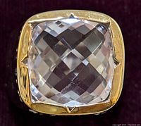 Close-up of the front crown showing a cushion-cut faceted pink amethyst gemstone with clear facets and a polished brass setting