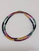 Full view of the multi-colored faceted bead necklace arranged in a circle on a white background.