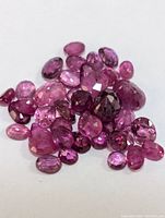 Photo showing an assortment of loose genuine ruby gemstones in faceted cuts of varying sizes and colors in the pink to deep red spectrum.