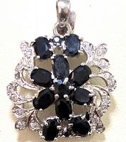 Front view of the sterling silver sapphire and cubic zirconia pendant displaying the floral arrangement of oval sapphires surrounded by clear CZ stones.