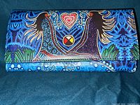Front view of the leather clutch purse displaying indigenous artwork with birds, heart, and medicine wheel on a blue background.