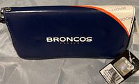 Front side of the Denver Broncos clutch purse showing navy blue with Broncos name and Denver text, original tags attached