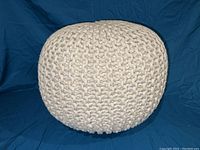 Top view showing chunky woven cotton blend texture of round footstool ottoman in cream.