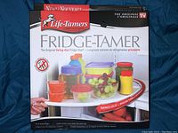 Front view of product box showing Life-Tamers branding, product name Fridge-Tamer, and image of shelf holding various containers and produce.