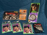 Full lot laid out including three character moustaches, zombie glasses, LED flashing teeth, nose putty, and zombie nail set all in original packaging.
