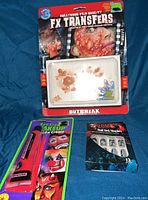 Full lot showing Hollywood FX Transfers with blister/pustule effects, Red Cream Makeup in bright red tube, and Zombie Nail Nail Set pack with 12 decorated nails.
