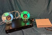 Front view of the setup showing the two light-up spherical speakers on top of the LG Blu-ray player and next to the white network switch.