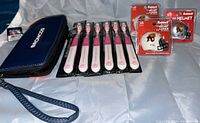 Lot taken showing Denver Broncos clutch purse, six Vancouver Canucks toothbrushes in original packaging, plus three CFL Calgary Stampeders mini helmets (two white, one silver) in original packaging.