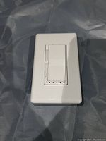 Front view of a white Wi-Fi enabled dimmer switch with a single rocker button and LED indicator dots below the rocker.