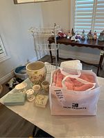 Photo of the bathroom linens bag, ceramic accessories including figurines and soap holders, and metal stand on table.