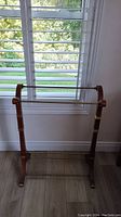 Front view of wood and metal blanket rack near window.