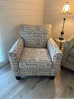Front view of the upholstered arm chair showing printed fabric and dark wood veneer feet.