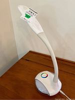 White OttLite LED desk lamp with flexible neck and rounded base, showing color temperature adjustment ring and charging port