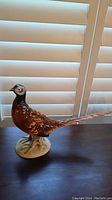 Angled side view of the porcelain pheasant figurine showing intricate painting and elongated tail.