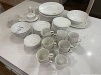Overview of all dishes arranged on countertop including plates, bowls, cups and serving pieces