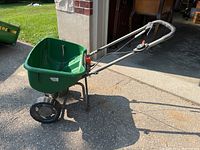 Full side and front angle view of the green Scotts Turf Builder seed spreader showing the hopper, wheels, and handle with controls.