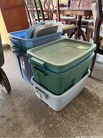 Photo of six stacked plastic storage bins including some with lids and others without, in blue, green, and gray colors.