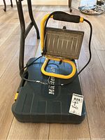 Yellow-framed work light resting on a Mastercraft hard plastic carrying case labeled with Maxsold sticker.