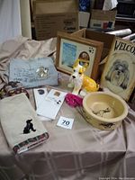 Photo showing full lot contents with tee shirt, framed tribute, ceramic dog, feeder bowl, welcome slate, wristlet, towel, notepads, and pink collar
