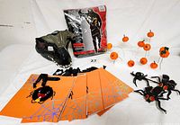 Full lot showing costume packaging, Indoraptor mask, Halloween gift bags with spider designs, rubber flies, plastic spider, and pumpkin picks.