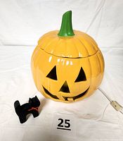 Ceramic pumpkin and wooden black cat figurine shown unlit, highlighting the glossy finish and carved details on the pumpkin, as well as the chip on the lid.