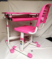 Side view of the child's desk and chair showing pink and white metal frame and plastic surfaces, highlighting adjustable legs and pull-out tray under the desk surface.