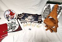 Overview photo showing wooden Christmas tree-shaped basket, Nordic Ware Christmas tree baking mold, snowman placemats, kitchen towels, and ceramic candle holders.