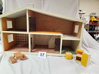 Front interior view of the vintage Lundby Sweden dollhouse showing six rooms over two floors with wallpaper, opening doors, carpet flooring and several pieces of yellow kitchen furniture including refrigerator, stove, and sink unit. Also includes three brown wooden box-style furniture items.