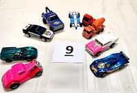 Nine die cast toy cars arranged on fabric background with number card 9 for identification.