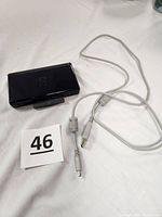 Closed black Nintendo DS Lite with charging cord coiled beside it