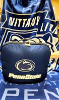 Penn State stadium cushion packed in its zippered case with Penn State throw blanket backdrop