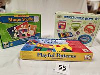 Photo shows all three boxed sets upright: Match It Shape Shuffle, Toddler Music Band, and Playful Patterns Design Activity with clear labeling and colorful packaging.