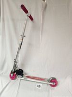 Front view of the Razor scooter showing pink wheels, footboard with logo, and adjustable handlebars with pink grips.