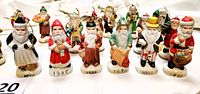 Set of nine Santa Claus figurines arranged in a row, showing front details of the figures dressed in period outfits with years labeled on bases.