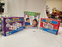 Three boxed educational games displayed side by side: Match It! Mathematics, Garanimals What's On My Head, and Match It! Spelling.