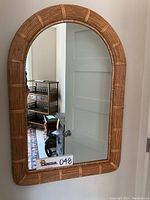 Front view of the bamboo wall mirror showing the curved top design and bamboo rod frame construction.