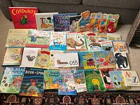 Full assortment of early learning and beginning reader board books arranged on floor with fabric storage basket behind them