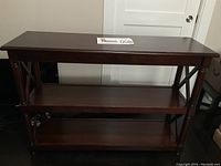 Front view of the Pier 1 Imports wooden sofa table showing three shelves and turned legs.