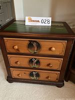 Front view of wooden cabinet showing three drawers with hand painted golfing figure portraits in circular frames.