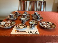 Full view showing eight cups, eight saucers, and eight low bowls arranged on table with lot number card.