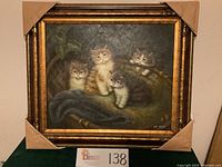 Close-up photo capturing details of the basket texture, kitten fur and painting signature.