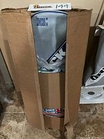 Front view of cardboard box showing gray and blue vacuum bag inside labeled XL2.