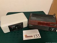 Sentry 1100 locking safe and Oreck XL Professional Air Purifier side by side on a green table.