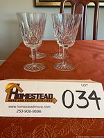 Four Waterford Lismore crystal goblets standing on a table, showing front view and detail of cut design.