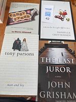 Four hardcover books arranged on a table showing their front covers: Candy Freak by Steve Almond, Man and Boy by Tony Parsons, The Last Juror by John Grisham, and a book by Danielle Crittenden.