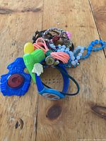 Group photo of assorted nostalgic items: blue Captain Crook reflector, digital watch, braided bracelets, Colonel Saunders pin, Green plastic whistle, Blue Jays ring