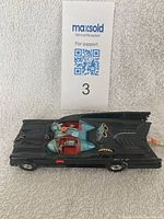 Top angled view of the black Batmobile model showing driver and passenger seats under clear canopy, Bat logos on sides, and rear fins.